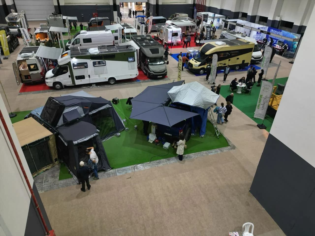 GitFest İzmir 2025'ten kare: motokaravanlar, kamp çadırları ve ziyaretçilerle dolu fuar holü